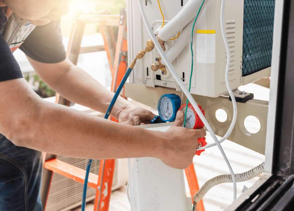 HVAC technician using manifold gauges to check pressure during an outdoor air conditioner repair